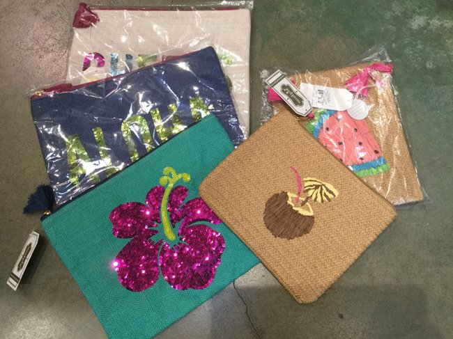 Various aloha-themed clutches available at Sunshine Swimwear in Waikiki Beach Walk® as a gift with purchase.