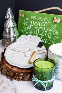 SoHa Living home goods including a white, pineapple-shaped plate, green candle, & green sign saying "wishing you peace, joy, & aloha"