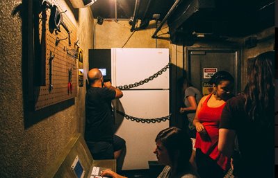 People in a dimly lit escape room searching for clues.