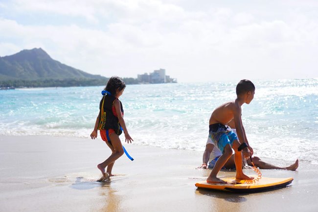 2 young children playing on a Hawaii beach in front of Diamond Head