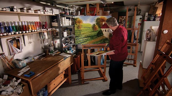 Alexandre Renoir paints a cottage in a room filled with art supplies