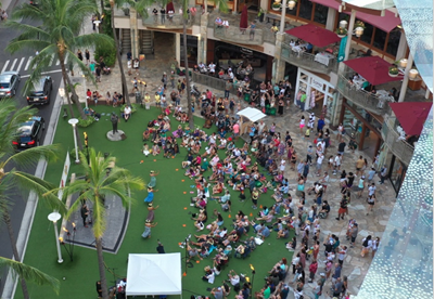 Aerial view of Waikiki Beach Walk's Plaza stage as a crowd gathers around to view a performance.