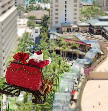 Santa Claus in a sleigh flies over a shopping mall, spreading holiday cheer in the night sky.