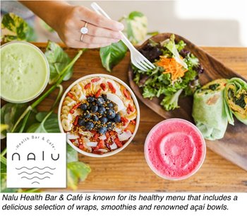 A person sitting at a table indoors, enjoying a colorful salad that includes various vegetables and garnishes. The setting is in a health-focused café known for its nutritious offerings.