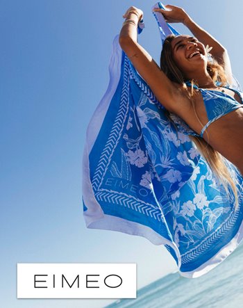 A woman in a bikini holds a blue towel, enjoying a sunny day at the beach.