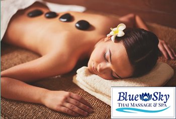 Woman receiving a hot stone massage with a flower in her hair, alongside the 'Blue Sky Thai Massage & Spa' logo