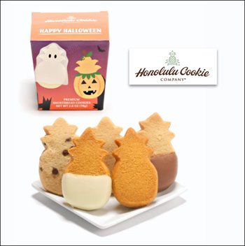 A plate of pineapple-shaped cookies of different flavors. The box behind the plate features a pineapple shape dressed as a ghost and a pineapple shaped jack-o-lantern.