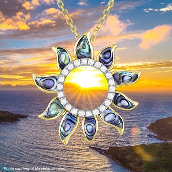 Sun-shaped gold pendant with abalone accents framing an ocean sunset