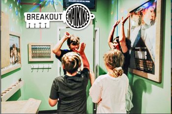 Group of people celebrating their escape at Breakout Waikiki, an escape room venue, surrounded by movie posters in a themed room